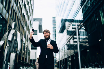 Cheerful adult entrepreneur taking selfie on street