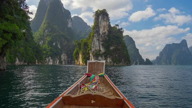 Boat trip on the lake Cheow Lan in Khao Sok National Park, Thailand. Famous "Three Sisters" karst formations rocks are seen in the distance. Magnificent nature of Thailand. HDR 4K shot