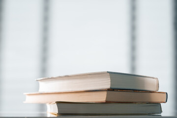 Books on the background of a window with blinds