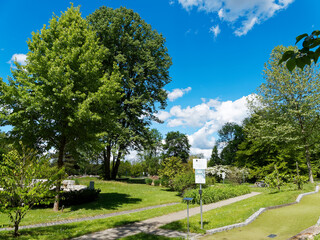 Fototapeta na wymiar Bad Bellingen im Markgräflerland (Bade-Wurtemberg) - Sentier de promenade, square et détente dans le parc au milieu de splendides parterres floraux entourés de hauts arbres sous un ciel bleu