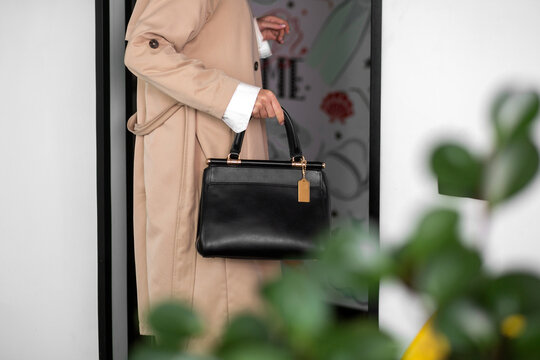 girl with a black bag in a trench coat. Luxury bag in the interior. Fashionable modern accessory. horizontal photo