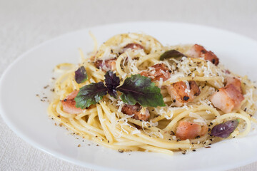 Pasta Carbonara. Spaghetti with bacon, parmesan cheese and basil on white plate on white background. Italian food concept. Selective focus.