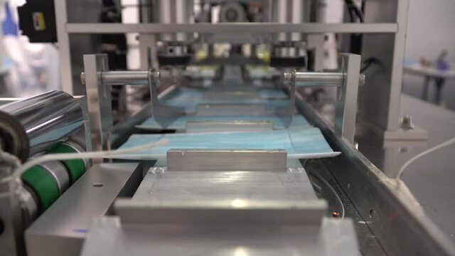 The process of manufacturing line production medical face mask with automatic machinery in an industrial factory . Shortages during the coronavirus pandemic or covid-19 outbreak