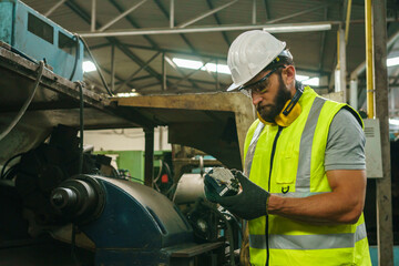 Engineer working at industrial machinery in factory. Manual workers cooperating while measuring a electronic.