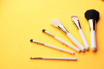 Makeup brushes with sparkles on a yellow background professional cosmetics