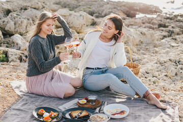 Two women female friends having picnic brunch with fresh homemade food and champagne.