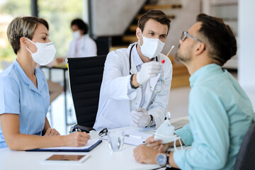 Male doctor testing a patient for coronavirus at medical pandemic.