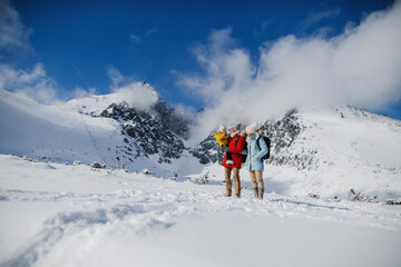Father and mother with small son in winter nature, standing in the snow.