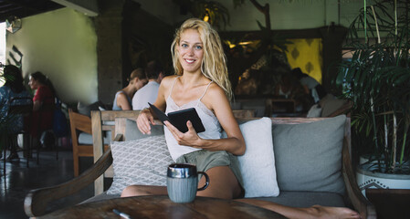Happy woman reading ebook in coffeehouse