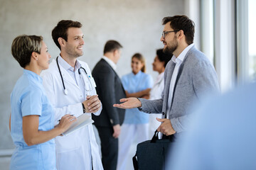 Businessman and doctor talking in a hallway at medical clinic.