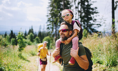 Family with small child hiking outdoors in summer nature.