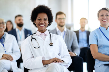 Happy black female doctor attending an educational event in convention center.