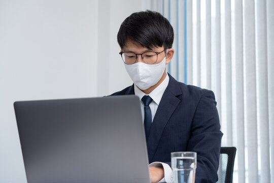 Asian Businessman In Glasses Wearing Protective Hygiene Mask Working On Laptop In Office For People Protect Themselves Coronavirus Pandemic, Covid 19 Quarantine