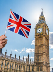 Fototapeta na wymiar Toursist in London holding flag of Great Britain in hand. Big Ben in background.