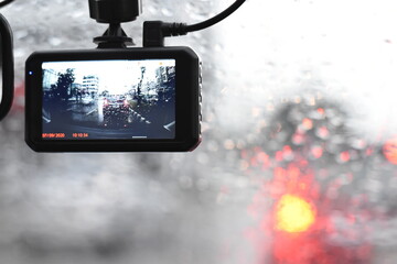 The car camcorder is recording traffic while it is raining.