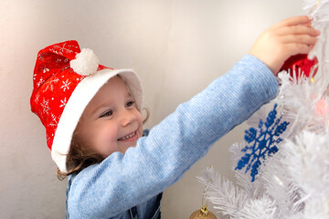 Happy little girl dresses up Christmas tree