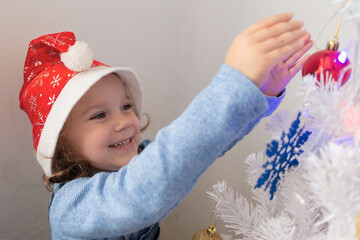 Happy little girl dresses up Christmas tree
