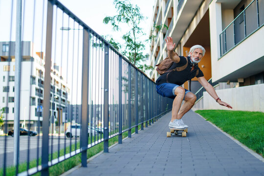 Portrait Of Mature Man Riding Skateboard Outdoors In City, Going Back To Work.