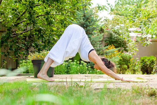 Young woman practices yoga in the garden - Parvatasana