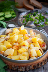 fried potatoes with chicken fillet in a portioned pan on a wooden table, selective focus