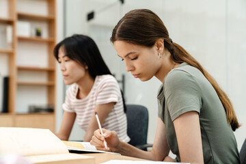 Photo of focused multinational students girls doing homework