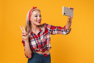 Image of girl making peace gesture and taking selfie on cellphone