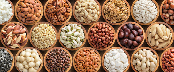 assorted nuts and seeds in wooden bowls, food background.