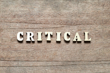 Alphabet letter block in word critical on wood background