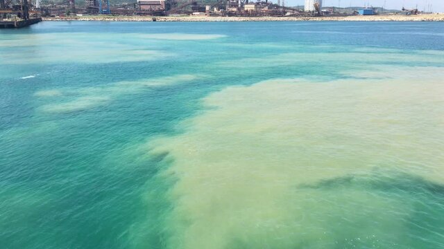 Yellow patches of polluted sea near industrial plants.