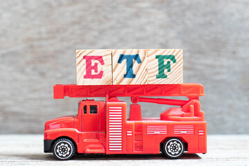Red fire truck hold letter block in word ETF (abbreviation of Exchange Traded Fund) on wood background