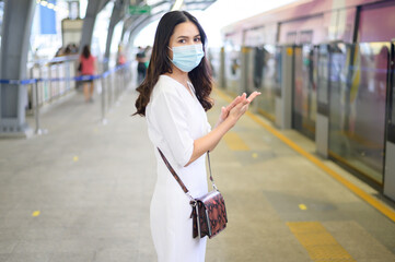 A young woman is standing on metro platform, wearing face mask , Covid-19 protection , New normal travel concept.