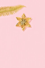 Christmas decorations, holidays background with golden colored toys in shape star and palm leaf. Minimal greeting card.
