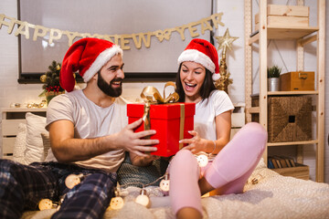 Fototapeta premium Merry Christmas and Happy New Year! Attractive young couple is celebrating holiday at home together.