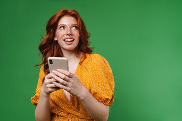 Image of ginger happy girl smiling and using mobile phone