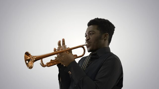 African american musician playing the trumpet expressively on gradient background.