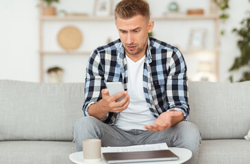 Sad adult man using smart phone at home