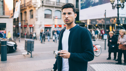Young man with photo camera standing on street