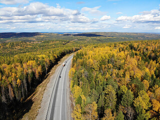 Road through autumn forest in Siberia from the air.
