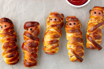 Scary sausage mummies in dough for kids party. Funny crazy Halloween food for children.