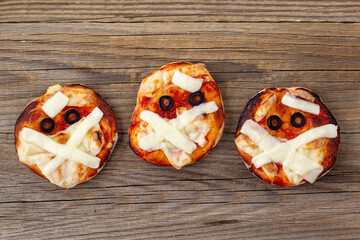 Mini pizza as mummy for kids with cheese, olives and ketchup. Funny crazy Halloween food for...