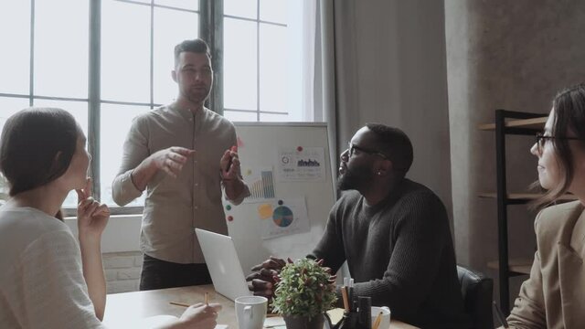 team of young colleagues conducting a business presentation using flipchart while working in the creative office