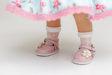 Doll legs in white socks and pink shoes on a light background. Imgra in dolls. Postcard, background...