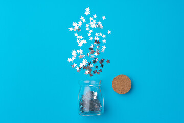 Glass jar with scattered confetti on blue background