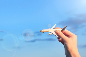 Airplane against blue sky. Woman's hand holds plane. Travel, departure concept. Transport