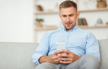 Handsome adult man using smartphone at home