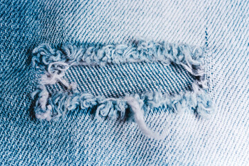 Hole on a denim light blue fabric.