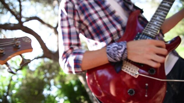 Musico tocando la guitarra electrica con una camisa de cuadros roja 