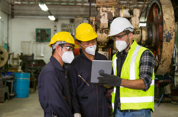 
European engineers are discussing work with Asian technicians using tablets in the factory.