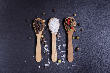 Salt and pepper mix in wooden spoons, top view