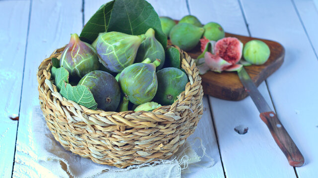 Higos verdes sobre sus hojas y un cesto de mimbre, fruta de temporada